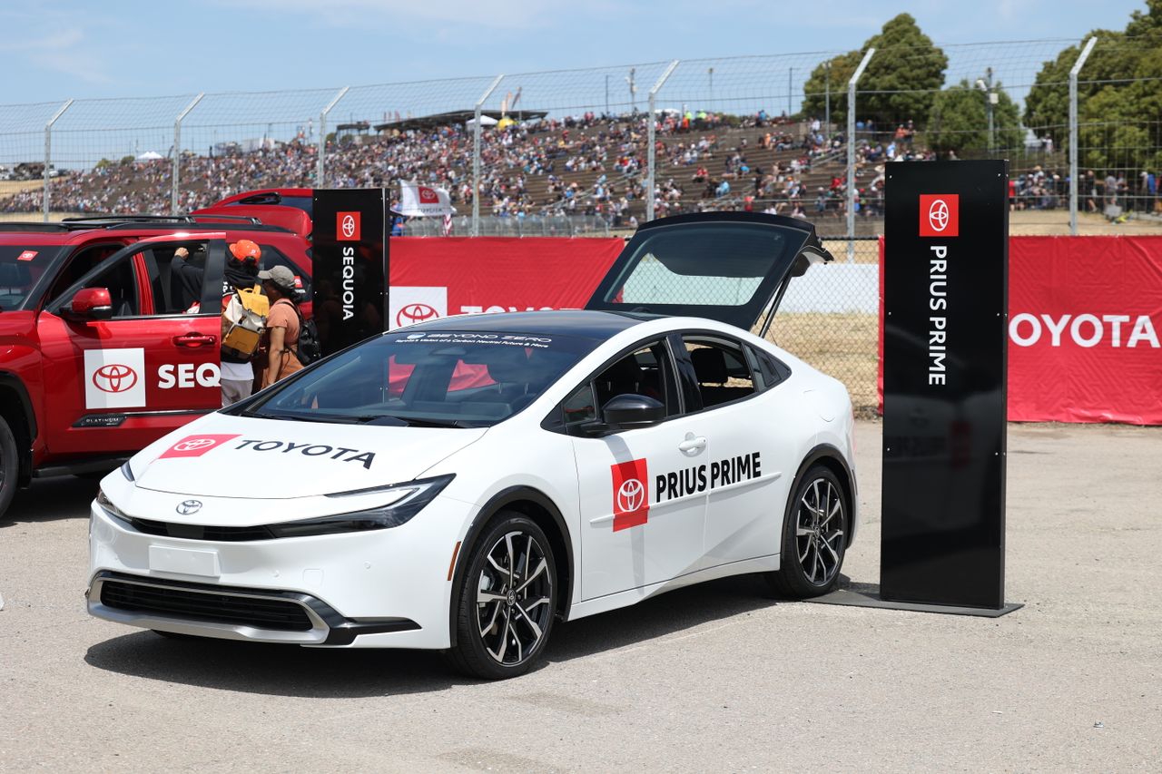 Crafting Captivating Headlines: Your awesome post title goes here A Toyota Prius Prime on display at an outdoor car exhibition with spectators in the background.
